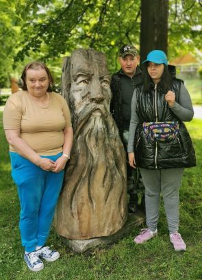 uczestnicy wycieczki  stojący przy drewnianej rzeźbie
