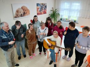 terapeutka z gitarą podczas zajęć z mieszkańcami