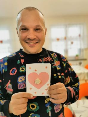 mieszkaniec pozuje do zdjęcia z kartką walentynkową