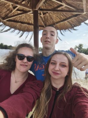 mieszkańcy z terapeutką pozują do zdjęcia na plaży pod parasolem