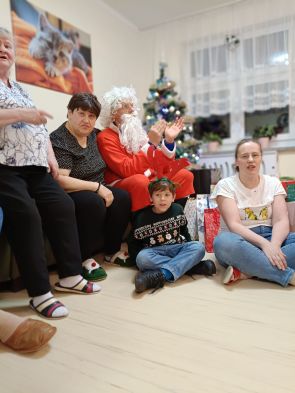 mikołaj z mieszkańcami i choinką w tle