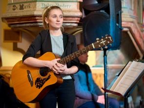 terapeutka domu wraz z gitarą i nutami podczas kolędowania w kościele