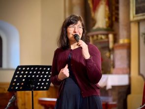 terapeutka domu w kościele podczas zapowiedzi koncertu, w tle wnętrze kościoła