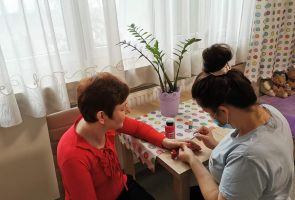 Opiekunka maluje paznokcie mieszkanki
