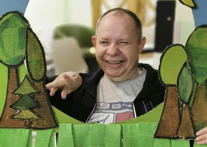uśmiechnięty mieszkaniec pozuje do zdjęcia z wykonaną pracą