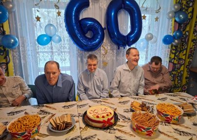 solenizant z gośćmi na tle symbolicznej liczby 60